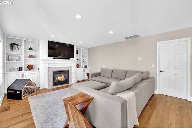 living room with built in shelves and light wood-type flooring