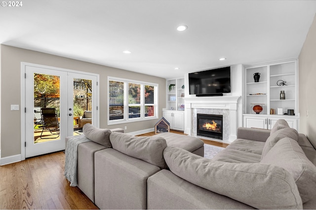 living room featuring light wood-type flooring, a fireplace, and french doors