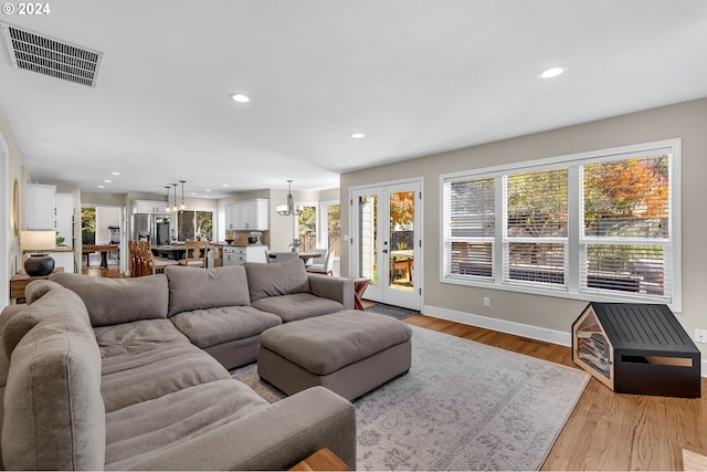 living room with a wealth of natural light, light hardwood / wood-style flooring, and a chandelier