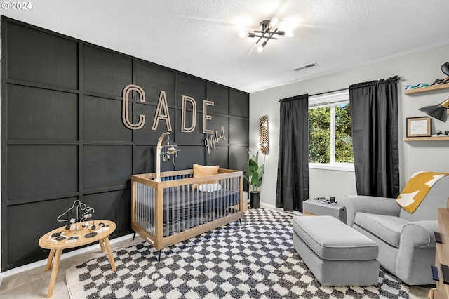 carpeted bedroom featuring a crib, a textured ceiling, and a chandelier