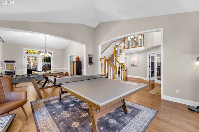 playroom with light hardwood / wood-style floors, an inviting chandelier, lofted ceiling, and french doors