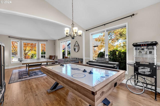 recreation room with a notable chandelier, plenty of natural light, vaulted ceiling, and light wood-type flooring