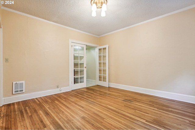 empty room with wood-type flooring, a textured ceiling, crown molding, and french doors