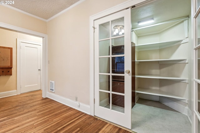 interior space featuring ornamental molding, hardwood / wood-style flooring, heating unit, and a textured ceiling