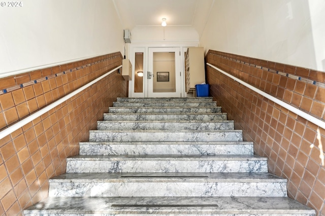 stairs featuring tile walls