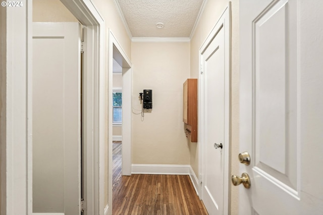 hallway featuring dark hardwood / wood-style floors, ornamental molding, and a textured ceiling