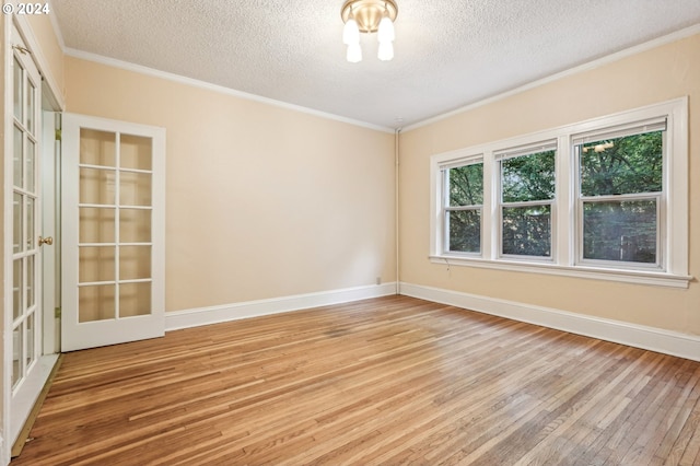 spare room featuring crown molding, a textured ceiling, and light wood-type flooring