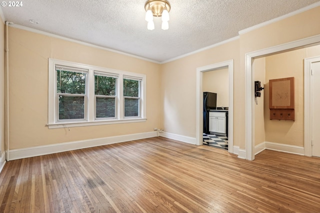 spare room featuring ornamental molding, a textured ceiling, and hardwood / wood-style floors