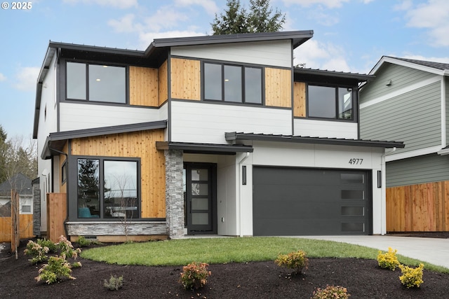 contemporary home with concrete driveway, fence, and a garage