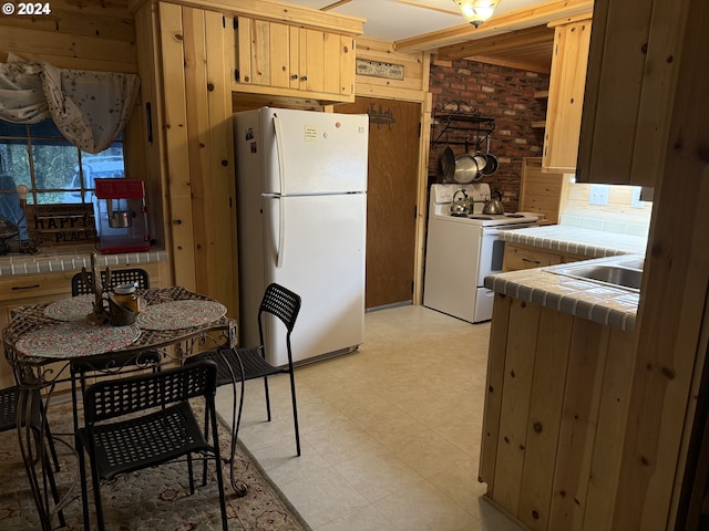 kitchen featuring decorative backsplash, brick wall, white appliances, wooden walls, and tile countertops