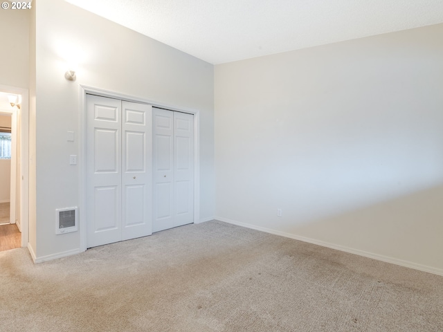 unfurnished bedroom with light colored carpet and a closet