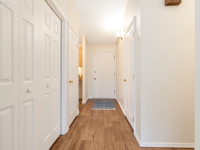 corridor featuring a textured ceiling and light hardwood / wood-style floors