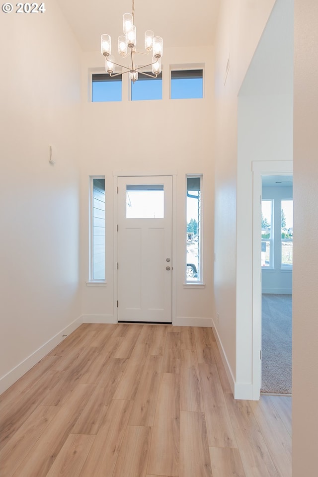 entrance foyer featuring a high ceiling, a notable chandelier, and light hardwood / wood-style flooring