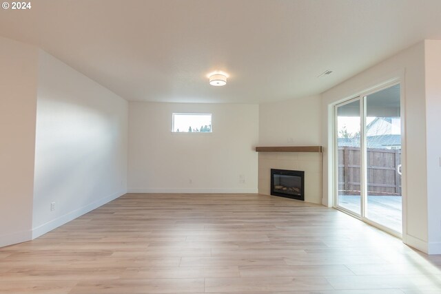 unfurnished living room featuring a fireplace, light wood-type flooring, and an inviting chandelier