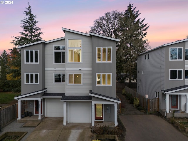 view of front of property with driveway, an attached garage, and fence