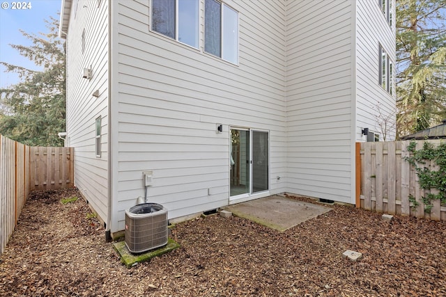 rear view of property with a fenced backyard and central AC