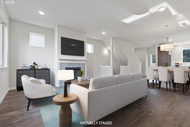 living room with a tiled fireplace and hardwood / wood-style floors