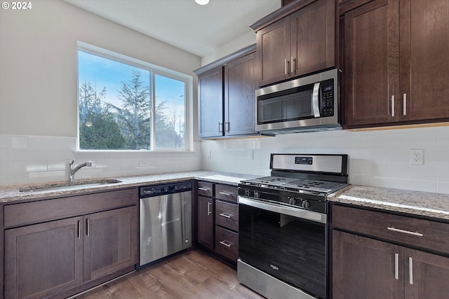 kitchen with appliances with stainless steel finishes, a sink, and dark brown cabinets