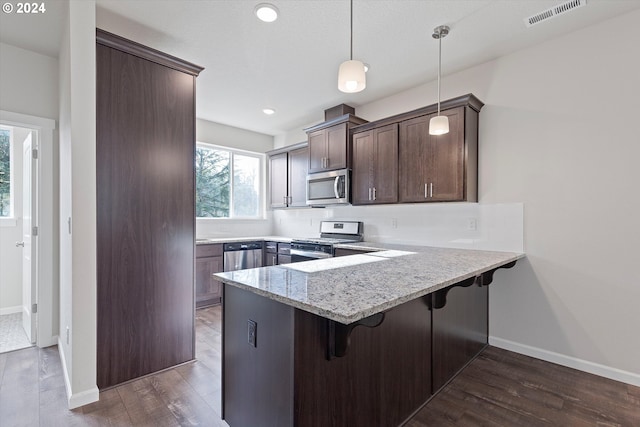 kitchen with stainless steel appliances, visible vents, dark wood-type flooring, a peninsula, and a kitchen breakfast bar