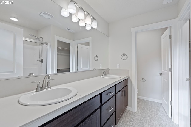 bathroom featuring double vanity, visible vents, toilet, a stall shower, and a sink