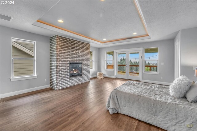 bedroom with french doors, a tray ceiling, access to exterior, and a textured ceiling