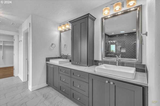 bathroom featuring vanity, a tile shower, and a textured ceiling