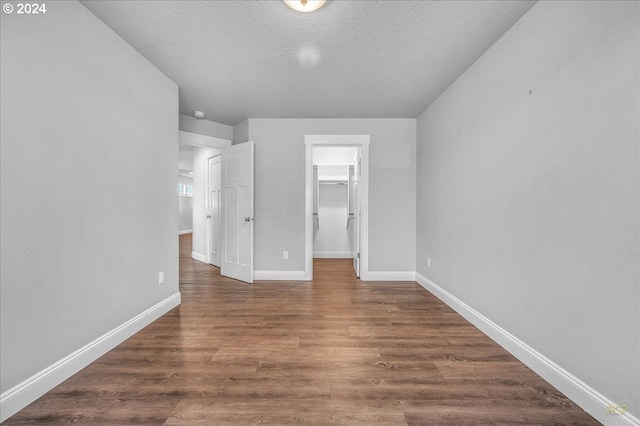 unfurnished bedroom with dark hardwood / wood-style flooring, a walk in closet, a closet, and a textured ceiling