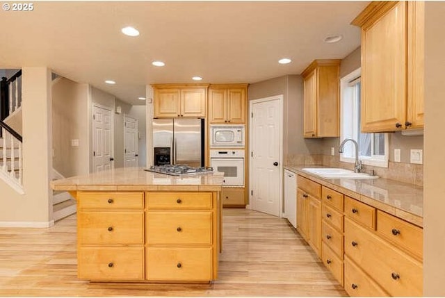 kitchen with light hardwood / wood-style flooring, light brown cabinetry, appliances with stainless steel finishes, sink, and a center island