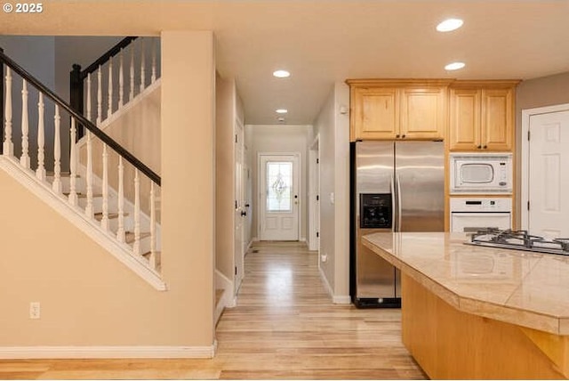 kitchen featuring light wood-type flooring, light brown cabinetry, appliances with stainless steel finishes, and tile counters