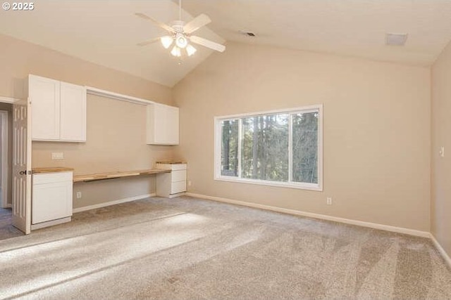 interior space featuring ceiling fan, built in desk, light carpet, and lofted ceiling with beams