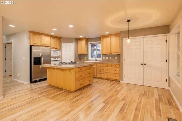 kitchen with pendant lighting, sink, a kitchen island, a breakfast bar area, and stainless steel appliances