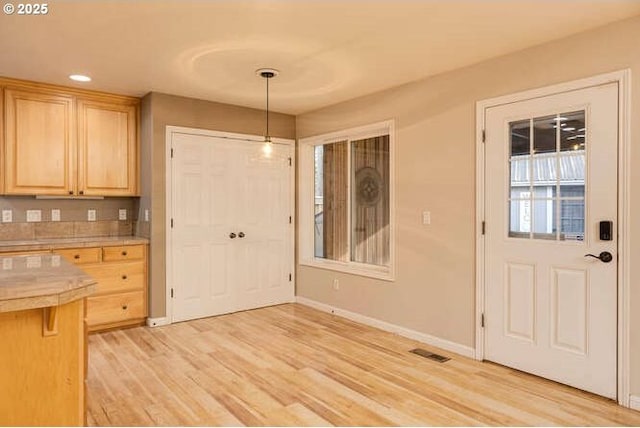 kitchen featuring decorative light fixtures, light wood-type flooring, tile countertops, and light brown cabinetry