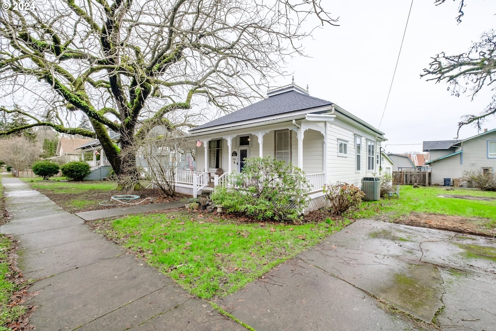 view of front facade with central AC unit, a front lawn, a porch, and fence