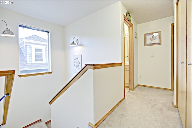 corridor featuring a textured ceiling and light carpet