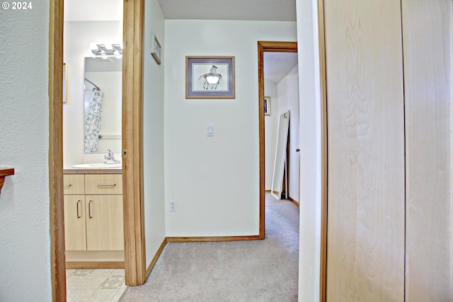 hallway with light carpet and sink