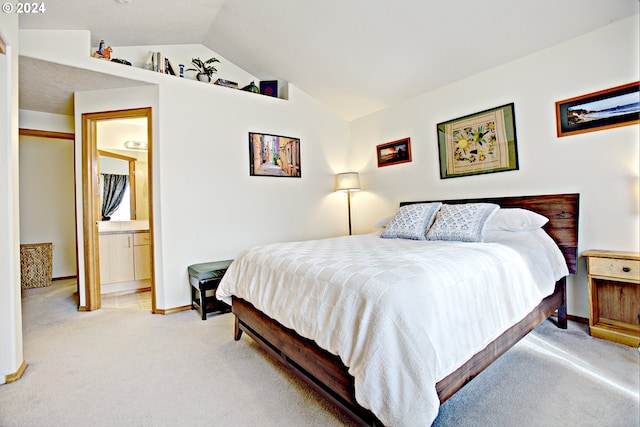 bedroom with ensuite bathroom, light carpet, and lofted ceiling