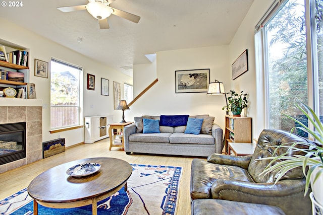 living room with a fireplace, light hardwood / wood-style floors, and ceiling fan