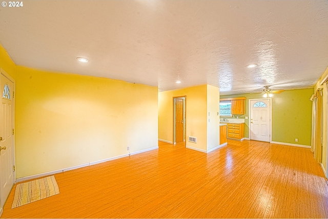 unfurnished living room with light wood-type flooring, ceiling fan, and a textured ceiling