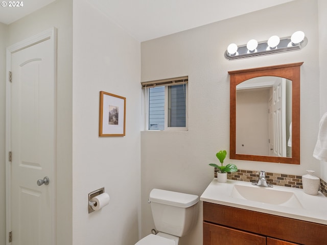 bathroom featuring vanity, toilet, and backsplash