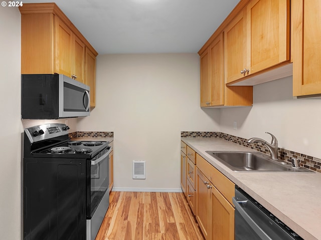 kitchen with light hardwood / wood-style floors, sink, appliances with stainless steel finishes, and tasteful backsplash