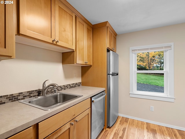 kitchen featuring light hardwood / wood-style floors, stainless steel appliances, sink, and decorative backsplash