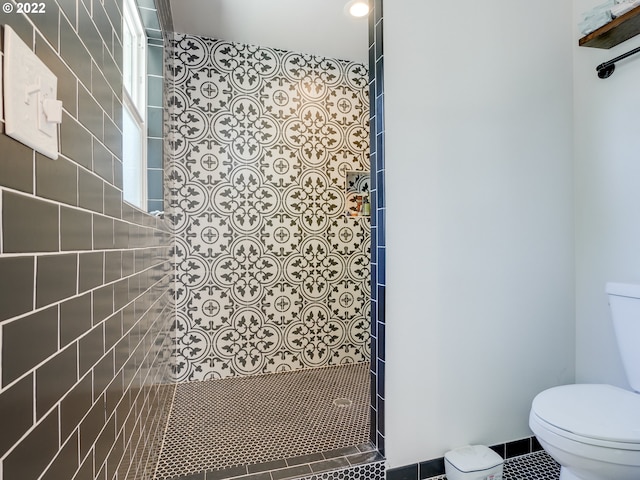 bathroom featuring tile patterned floors, tiled shower, and toilet