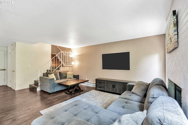 living room with a large fireplace, a baseboard heating unit, and dark hardwood / wood-style floors