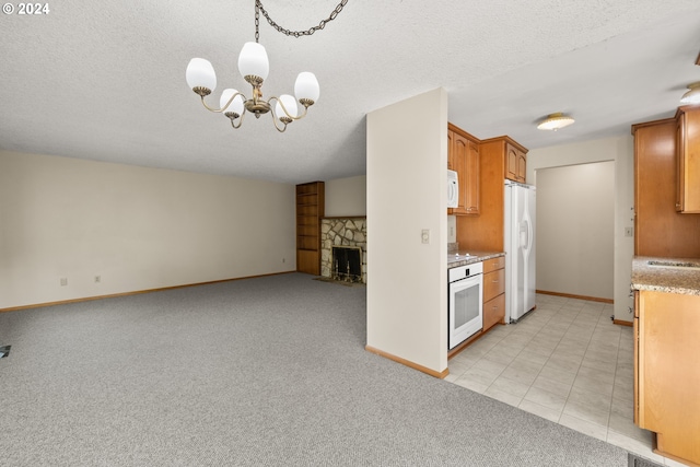 kitchen with a fireplace, an inviting chandelier, white appliances, light colored carpet, and pendant lighting