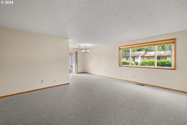 spare room featuring carpet flooring, an inviting chandelier, and a textured ceiling