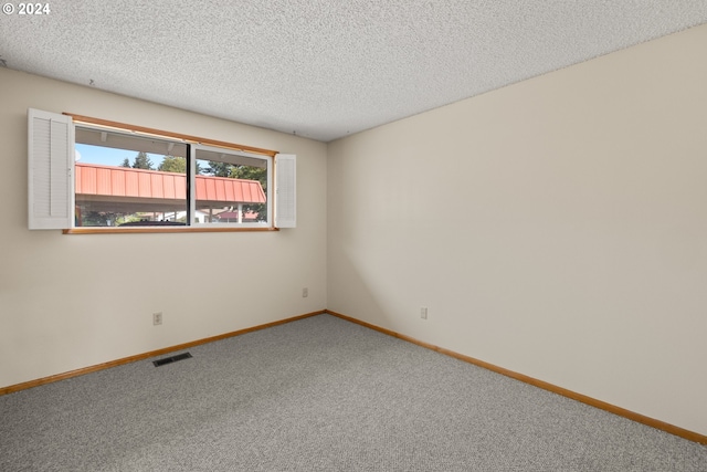 carpeted empty room featuring a textured ceiling