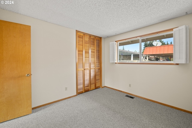 carpeted empty room featuring a textured ceiling