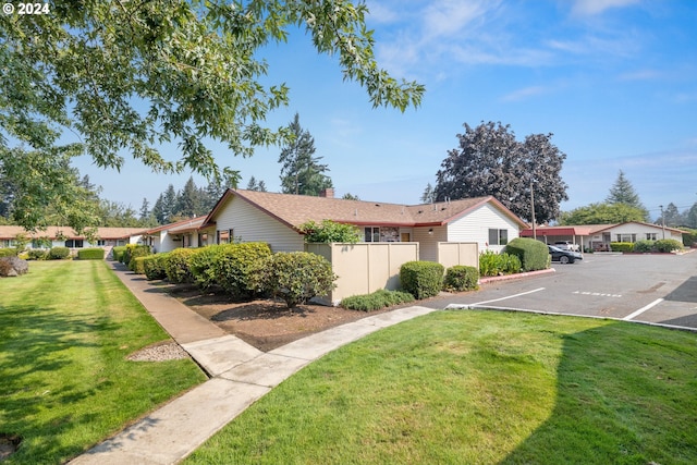 view of property exterior with a yard, uncovered parking, and fence