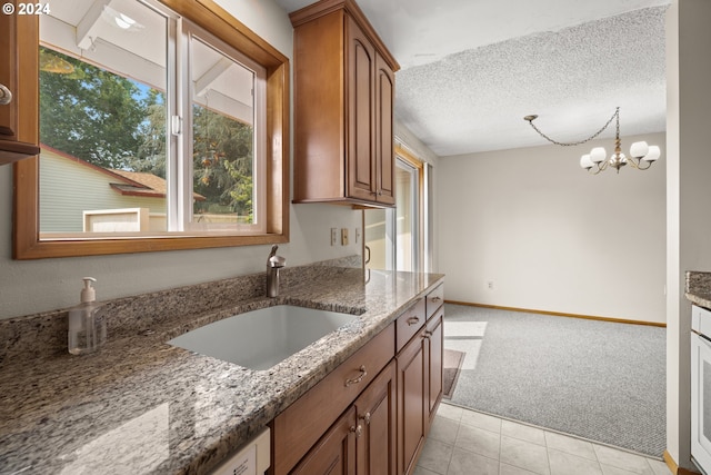 kitchen featuring light stone countertops, an inviting chandelier, sink, and a textured ceiling