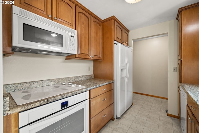 kitchen with white appliances, light tile patterned floors, and light stone countertops